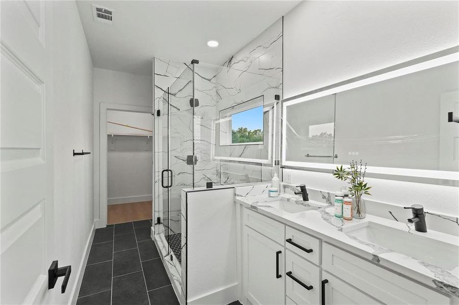 Bathroom with a shower with shower door, double vanity, and tile patterned floors