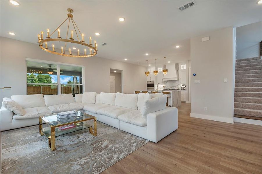 Living room featuring sink, light hardwood / wood-style flooring, and an inviting chandelier