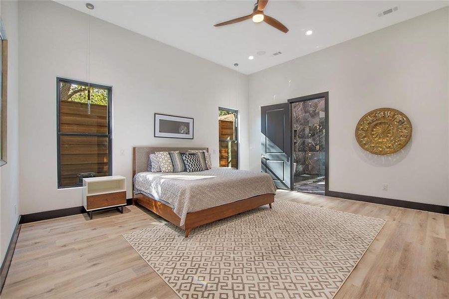 Bedroom featuring access to outside, light wood-type flooring, ceiling fan, and a towering ceiling