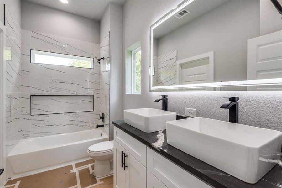 Full bathroom with tiled shower / bath combo, vanity, tile patterned floors, and toilet