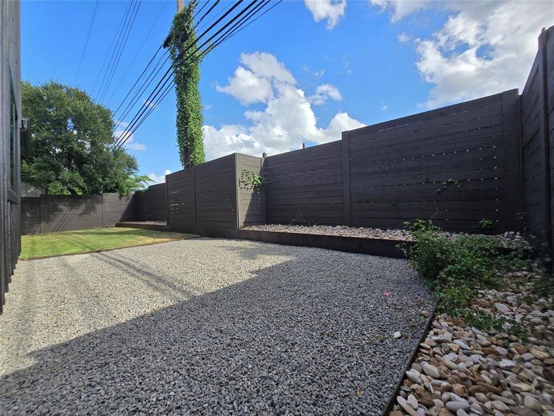 Back yard overview with multiple areas - one half with grass, another part with xeriscape/stone. Add potted plants on top of the metal retaining walls for your custom touch.