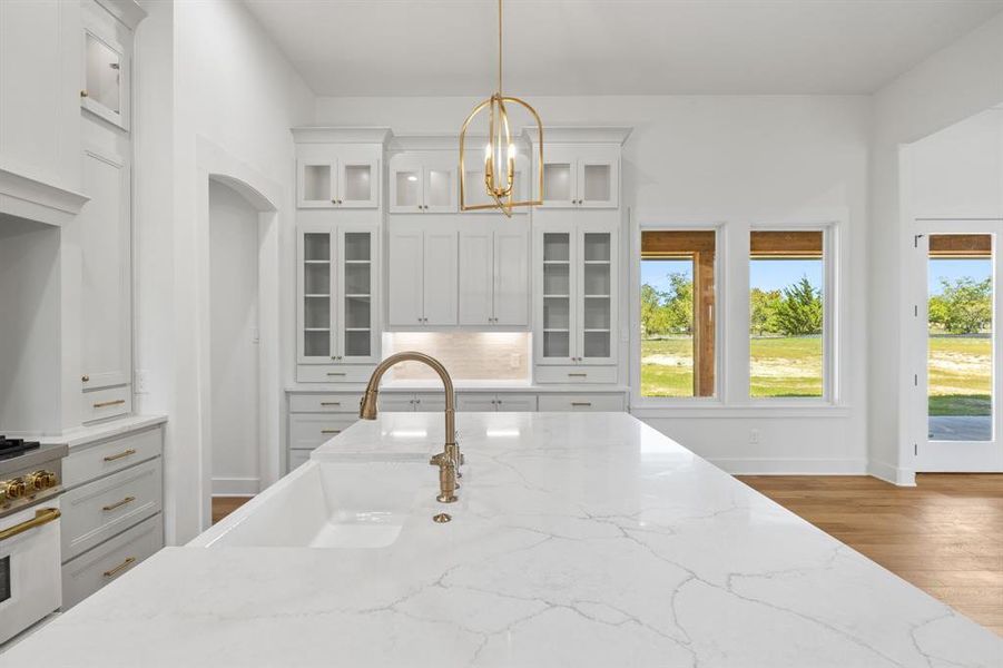 Kitchen featuring pendant lighting, light stone countertops, and a healthy amount of sunlight