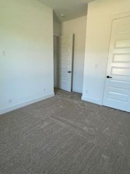 Unfurnished bedroom with dark colored carpet