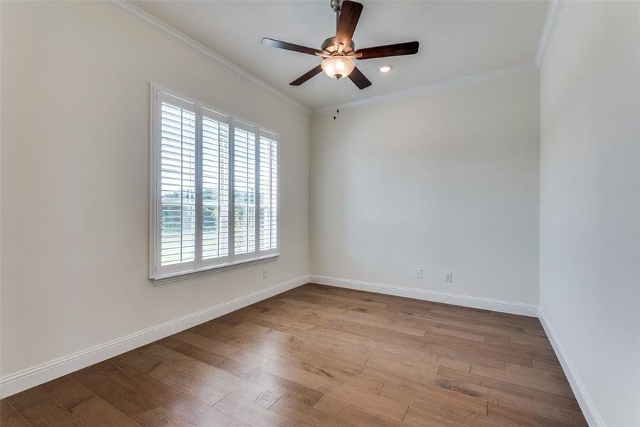 Study with wood flooring on front of house with exquisite Plantation shutters