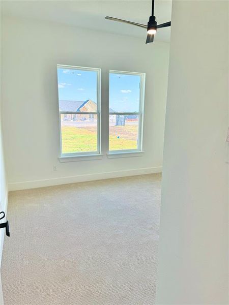 Empty room with light carpet, a healthy amount of sunlight, and ceiling fan