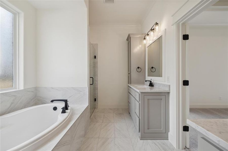 Bathroom featuring shower with separate bathtub, vanity, and crown molding