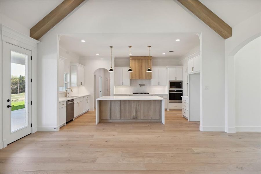 Kitchen featuring white cabinetry, lofted ceiling with beams, hanging light fixtures, and a kitchen island