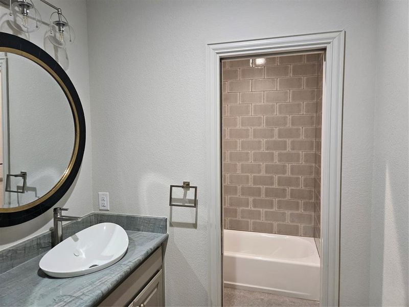 Bathroom featuring vanity and tiled shower / bath