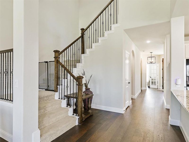 Staircase featuring a towering ceiling, hardwood / wood-style floors, and an inviting chandelier