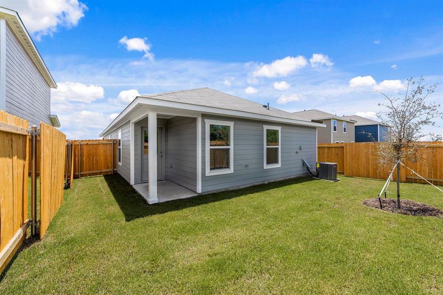 Rear view of property with central air condition unit and a lawn