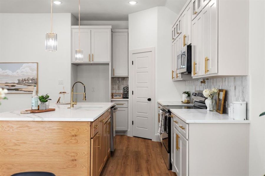 Kitchen with decorative light fixtures, light stone countertops, stainless steel appliances, and white cabinets