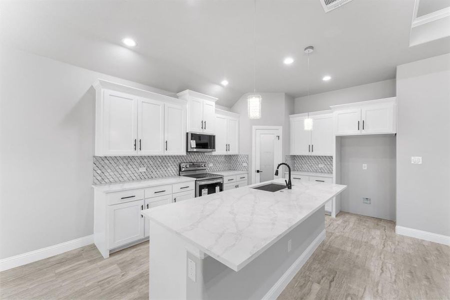 Kitchen featuring stainless steel appliances, white cabinets, a kitchen island with sink, and sink