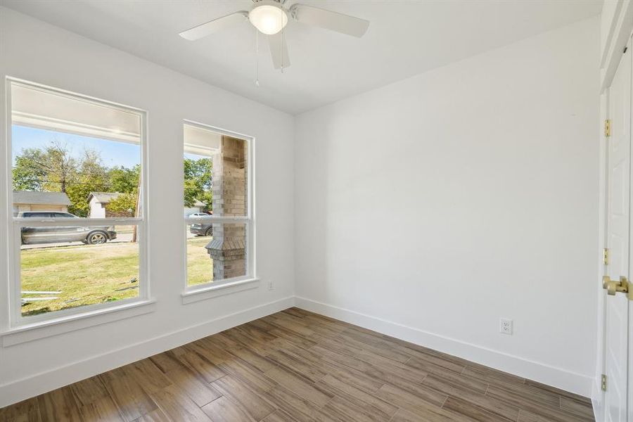 Unfurnished room featuring ceiling fan, wood-type flooring, and a wealth of natural light