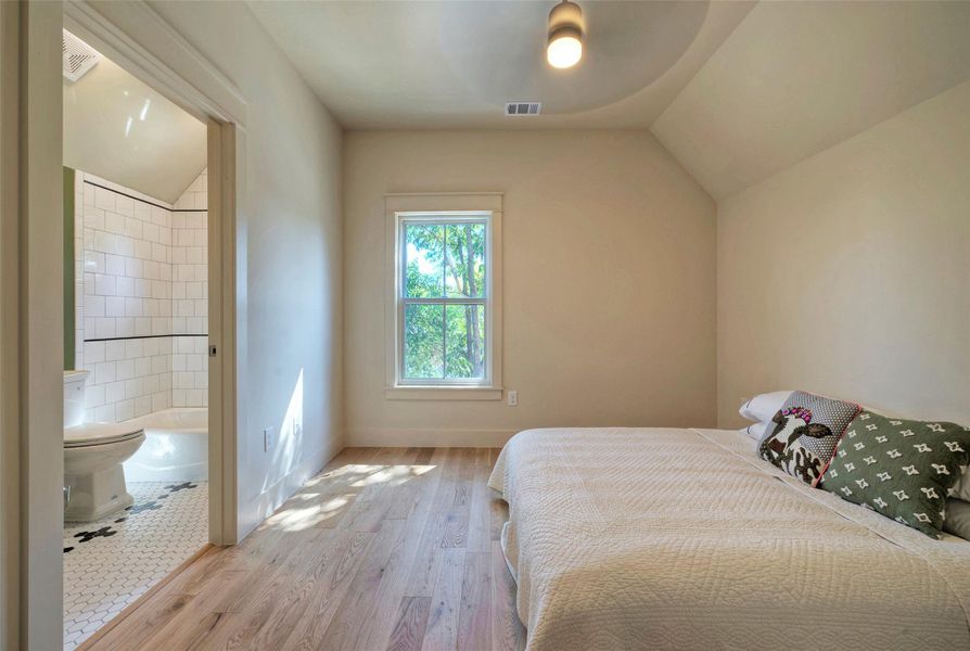 Primary suite has hardwood floors, walk-in closet and a glamorous full bath