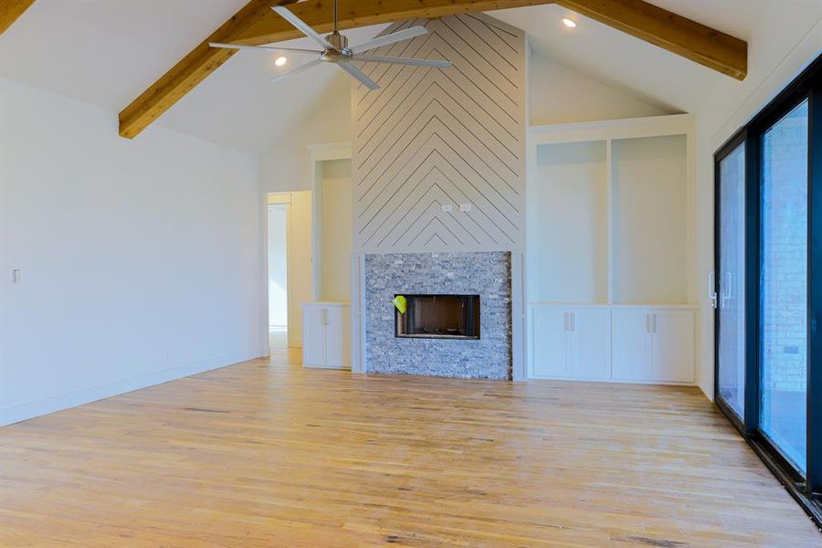 Unfurnished living room featuring beamed ceiling, high vaulted ceiling, ceiling fan, and light wood-type flooring