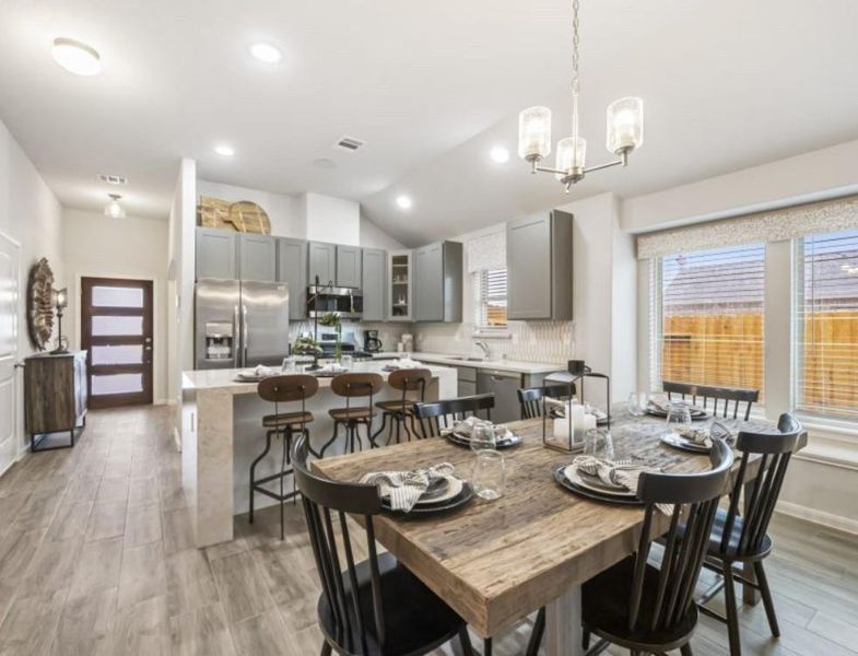 Experience the heart of the home in this expansive kitchen and dining area. The kitchen features a large island with quartz countertops, modern stainless steel appliances, and ample cabinetry. The adjacent dining area is perfect for family gatherings, with plenty of natural light streaming through the windows. The open layout ensures seamless interaction between the kitchen and dining spaces, making it ideal for entertaining. **This image is from another Saratoga Home with similar floor plan and finishes.