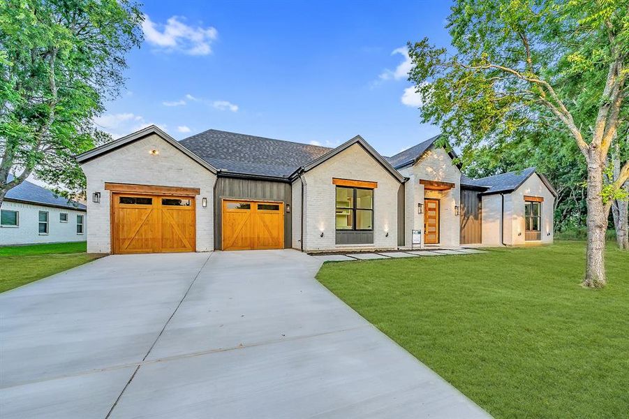 Modern farmhouse style home featuring a front lawn and a garage. Sod in photos is for visual aid purposes.