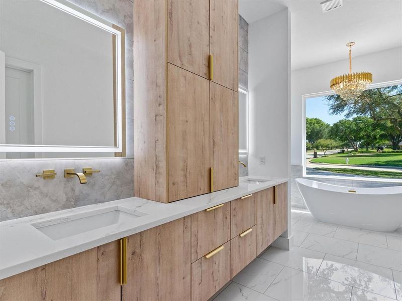 Bathroom featuring an inviting chandelier, tile walls, a tub to relax in, and vanity