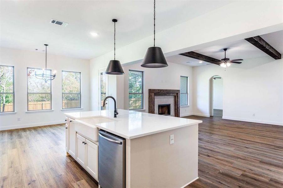 Kitchen featuring dark hardwood / wood-style flooring, decorative light fixtures, sink, and an island with sink