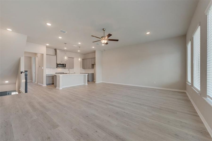 Unfurnished living room with sink, ceiling fan, and light hardwood / wood-style floors