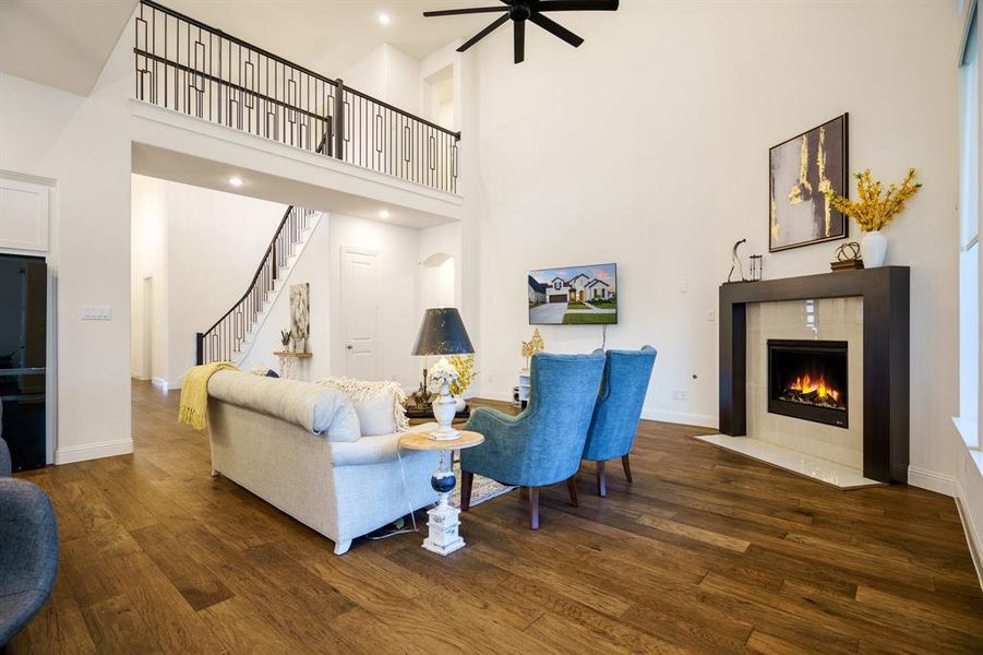 Living room featuring a tiled fireplace, dark hardwood / wood-style floors, and a towering ceiling