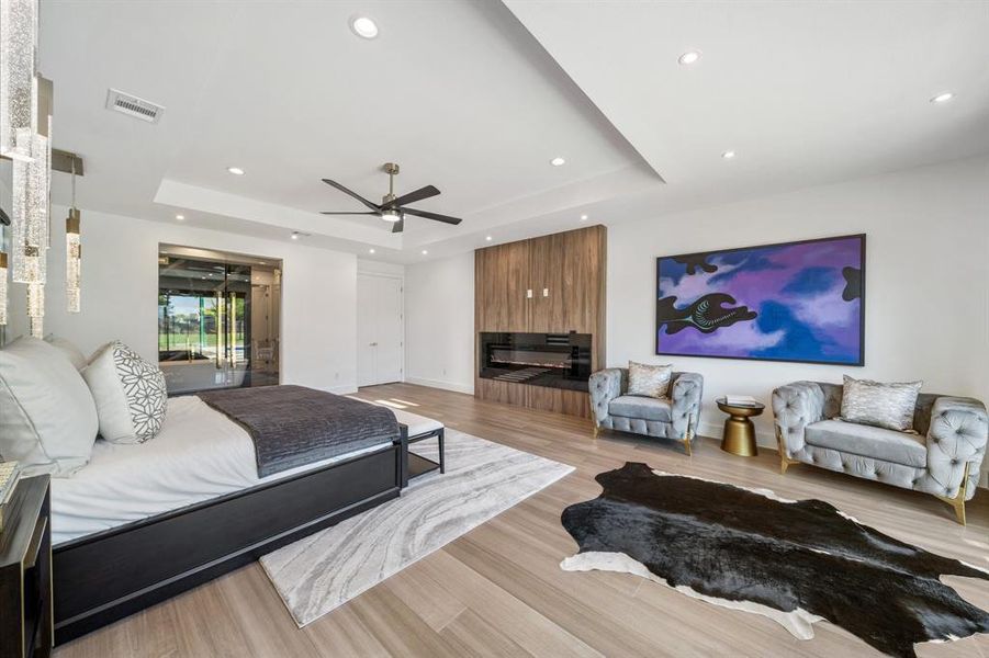 Bedroom featuring ceiling fan, light hardwood / wood-style flooring, and a raised ceiling