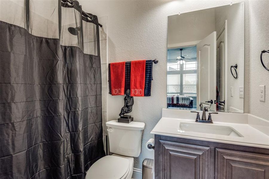 Bathroom with ceiling fan, vanity, walk in shower, and toilet