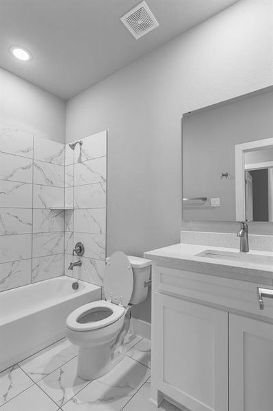 Full bathroom with tiled shower / bath combo, vanity, and toilet