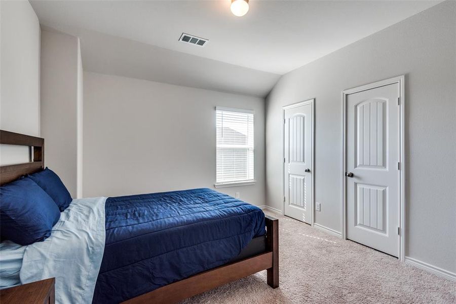 Carpeted bedroom featuring vaulted ceiling