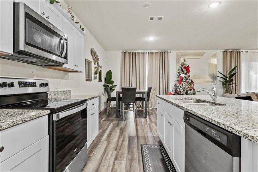 Kitchen with white cabinets, sink, wood-type flooring, and stainless steel appliances