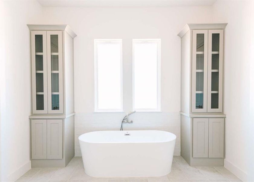 Bathroom with tile walls, tile patterned flooring, and a bath