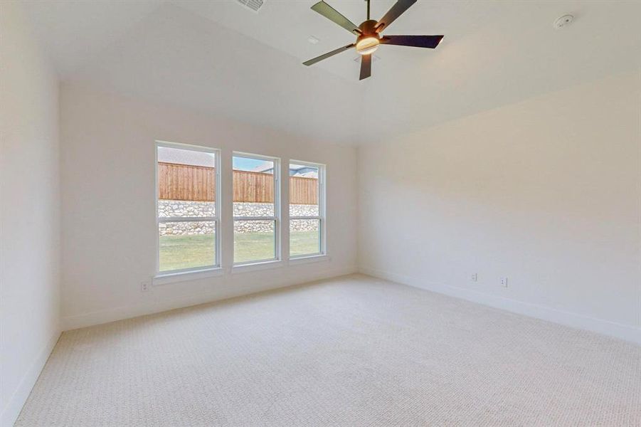 Carpeted empty room featuring high vaulted ceiling and ceiling fan