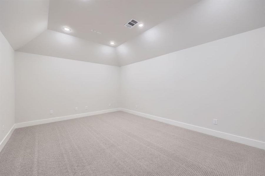 Carpeted spare room featuring vaulted ceiling