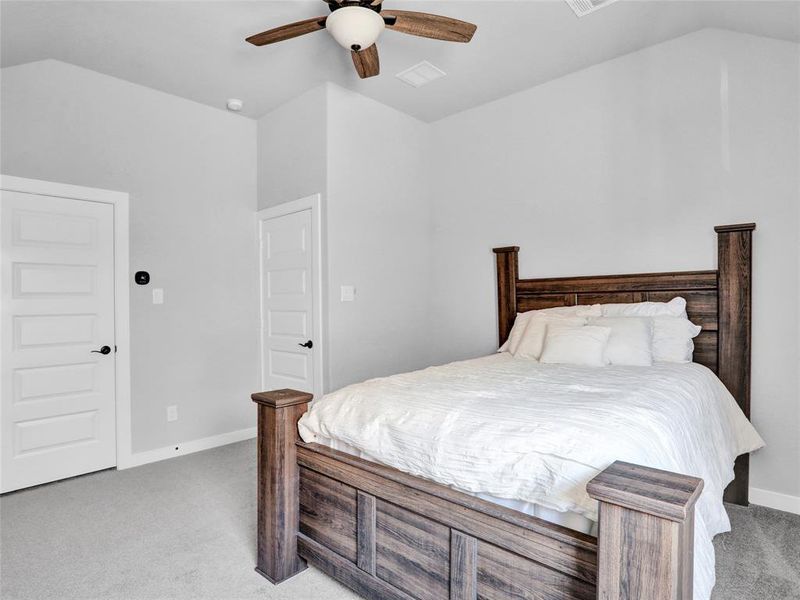 Upstairs bedroom with ceiling fan and vaulted ceiling