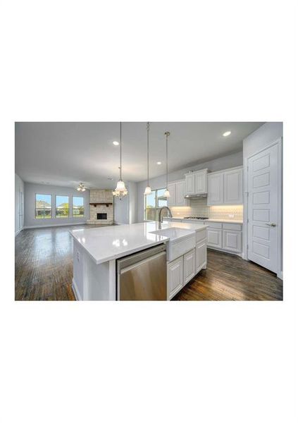 Kitchen with white cabinetry, a fireplace, an island with sink, dark hardwood / wood-style flooring, and stainless steel dishwasher