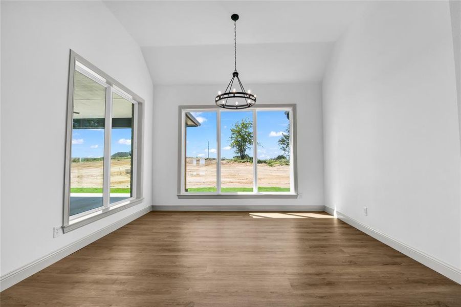 Unfurnished dining area with a chandelier, vaulted ceiling, and dark hardwood / wood-style flooring