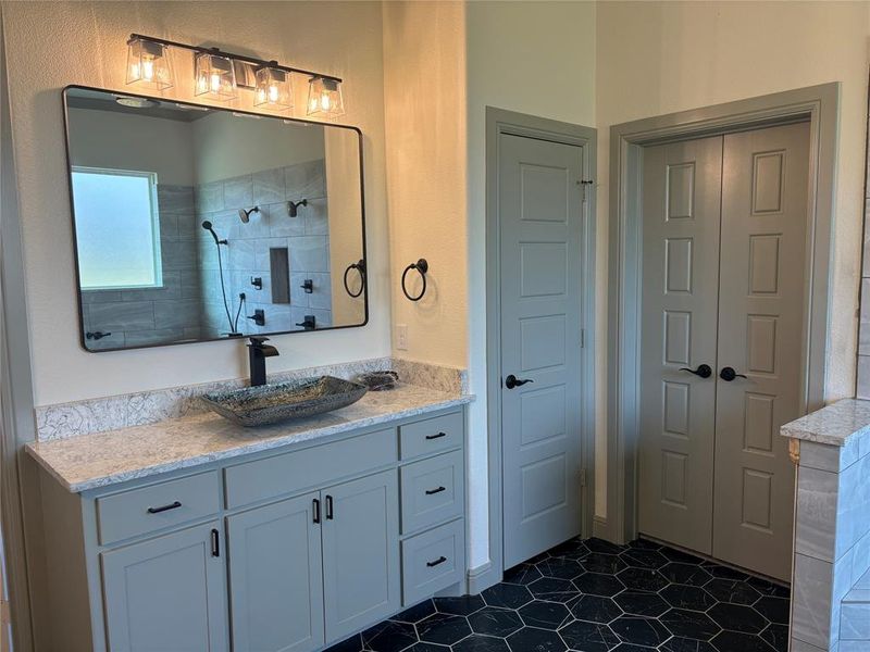 Bathroom featuring tile patterned floors, vanity, and tiled shower