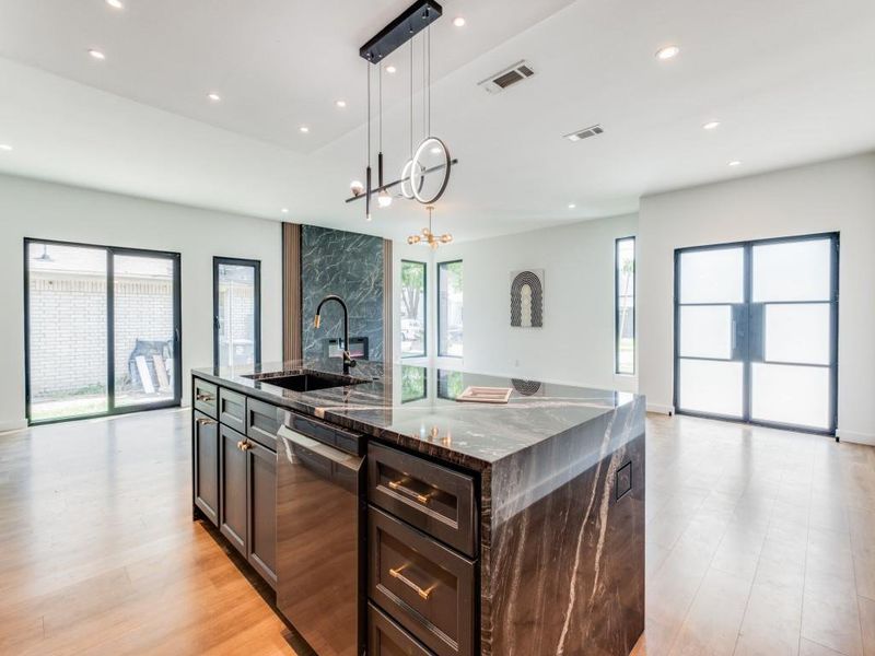 Kitchen featuring hanging light fixtures, stainless steel dishwasher, a large island, dark stone countertops, and a notable chandelier