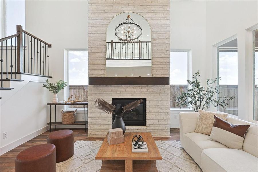 Living room featuring a large fireplace, a high ceiling, hardwood / wood-style flooring, and a chandelier