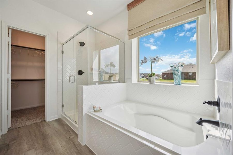 Indulge in luxury in this spa-inspired primary bathroom, showcasing a spacious walk-in shower with a stunning tile surround. Light-colored cabinets paired with granite countertops enhance the serene atmosphere. Sample photo of completed home with similar floor plan. As-built color and selections may vary.