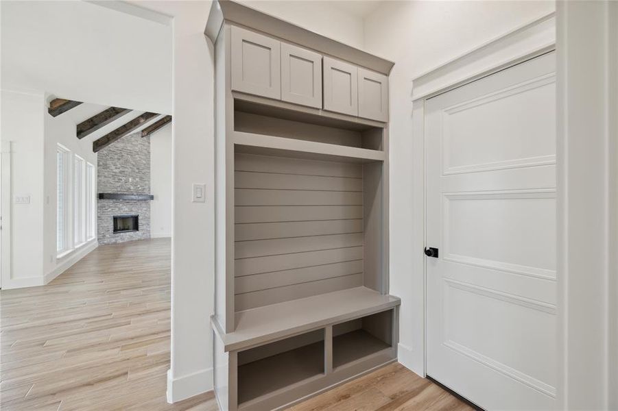 Mudroom featuring light wood-type flooring and a stone fireplace