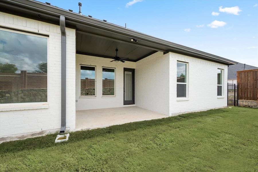 Rear view of property with a patio area, a yard, and ceiling fan