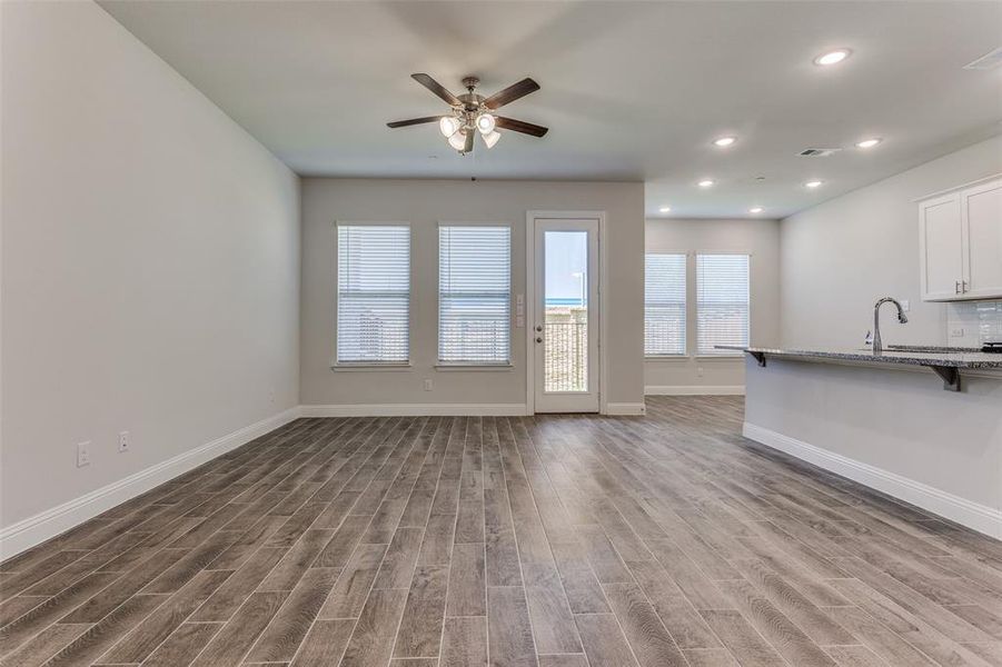 Unfurnished living room with hardwood / wood-style floors, sink, and ceiling fan