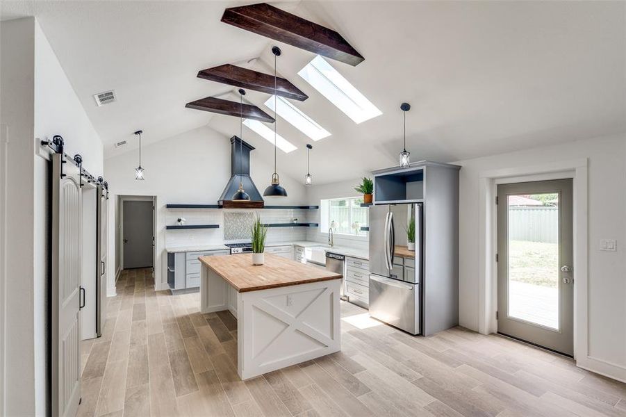 Stunning oversized Kitchen with 12 ft custom island, beamed ceilings, stunning skylights, floating kitchen shelves, soft close drawers, oversized range and massive custom hood all overlooking the oversized lot!