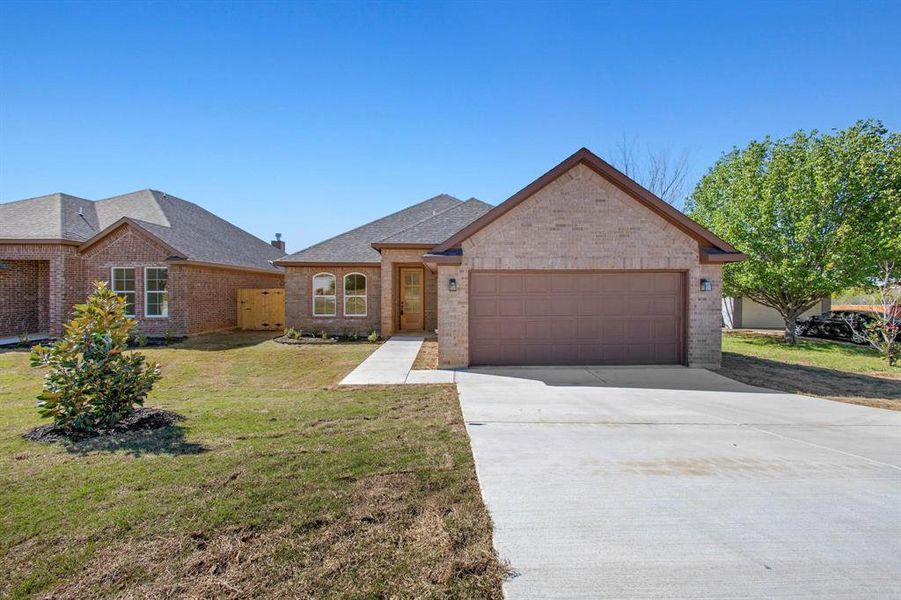 Ranch-style house featuring a garage and a front yard