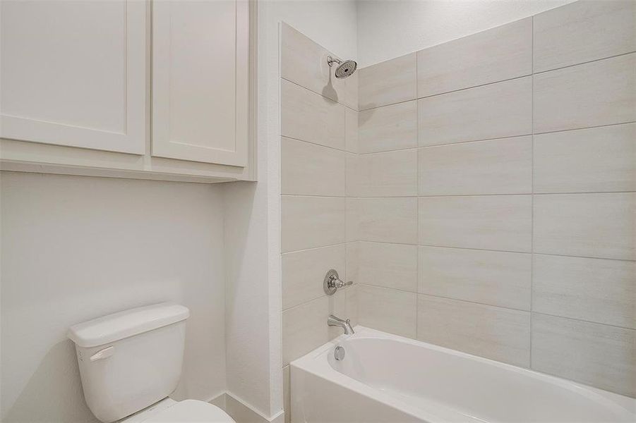 Bathroom featuring tiled shower / bath combo and toilet