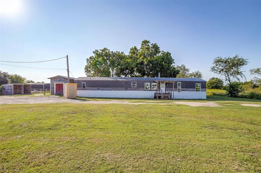 View of front of home featuring a storage shed and a front yard