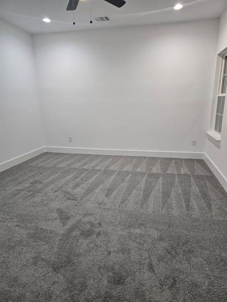 Carpeted empty room featuring ceiling fan