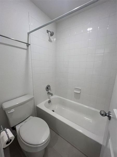 Bathroom featuring toilet, tile flooring, and tiled shower / bath combo