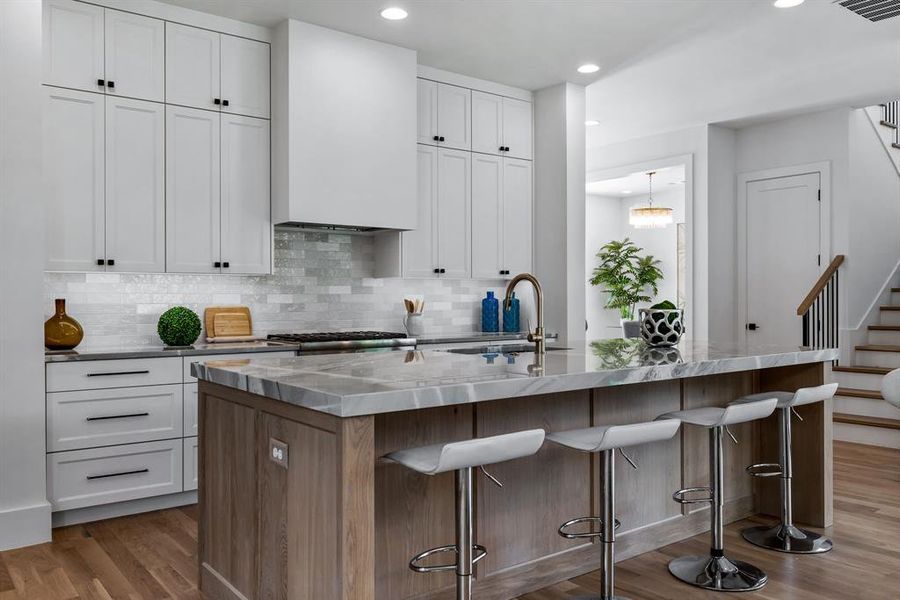 Kitchen featuring a kitchen island with sink, hardwood / wood-style flooring, and white cabinetry